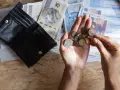 Dłonie liczą monety i banknoty obok otwartego portfela. Szybka, bezpieczna chwilówka to rozwiązanie, gdy brakuje gotówki.