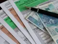 Formularze PIT, długopis i polskie banknoty. Miesięczna kwota wolna od podatku jest ważnym elementem rozliczeń.
