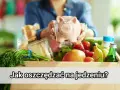 Różowa świnka-skarbonka w rękach kobiety nad pudełkiem pełnym świeżych warzyw i owoców. Podpis: Jak oszczędzać na jedzeniu?