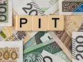 Litery "PIT" na tle polskich banknotów. Może oznaczać dużą niedopłatę podatku, która wymaga uzupełnienia.