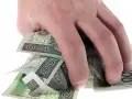 Dłoń trzyma plik polskich banknotów 100 zł. Może to symbolizować zwrot refinansowania lub po prostu oszczędności.