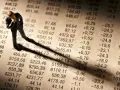 Figurka biznesmena pochyla się nad tabelą finansową, sugerując zmartwienie nowym podatkiem od lokat.