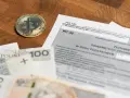 Złoty bitcoin obok formularza PIT-38 i polskich banknotów. Może to oznaczać niedopłatę podatku 3 zł.