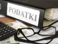 Segregator z napisem "PODATKI", kalkulator, okulary i dokumenty. Tabela kwota wolna od podatku 30 tys. jest częścią tych dokumentów.