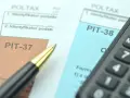 Dwa formularze podatkowe, PIT-38 i PIT-37, leżą obok siebie, gotowe do wypełnienia. Obok leży długopis i kalkulator.