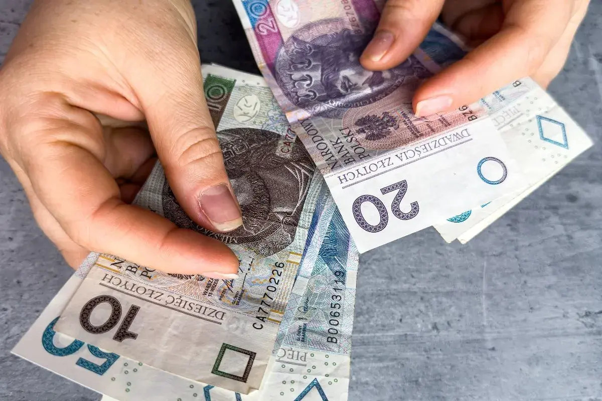 Ręce trzymają polskie banknoty 10, 20 i 50 zł. Czy w Vivus można przedłużyć pożyczkę?