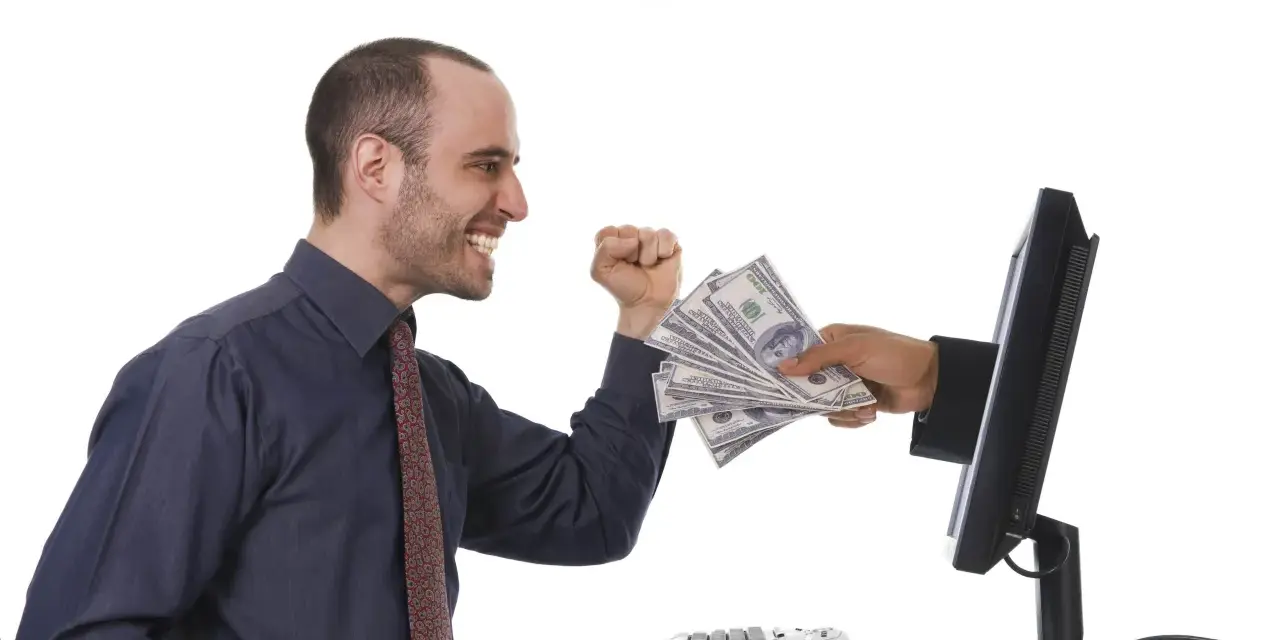 Uśmiechnięty mężczyzna otrzymuje stos banknotów z ekranu komputera. To symbol zarabiania na klikaniu.