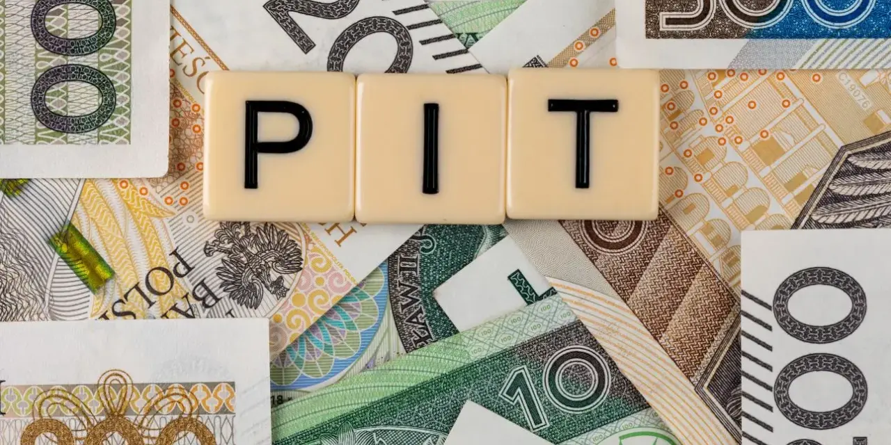 Litery "PIT" na tle polskich banknotów. Może oznaczać dużą niedopłatę podatku, która wymaga uzupełnienia.