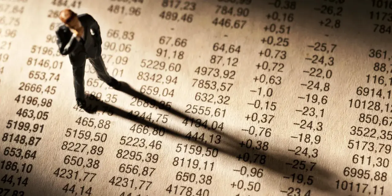 Figurka biznesmena pochyla się nad tabelą finansową, sugerując zmartwienie nowym podatkiem od lokat.