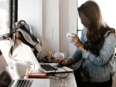 Kobieta pracuje przy laptopie, pijąc kawę. To idealne miejsce do rozwijania swoich freelancer zarobki.