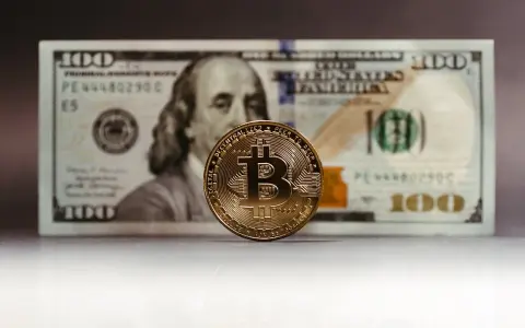 Złoty Bitcoin na tle banknotu 100 dolarów. Zastanawiasz się, jak rozliczyć podatek od zysku z kryptowalut?