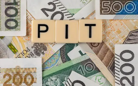 Litery "PIT" na tle polskich banknotów. Może oznaczać dużą niedopłatę podatku, która wymaga uzupełnienia.