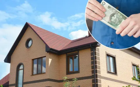 Dom z cegły pod błękitnym niebem. W rogu widać dłoń trzymającą banknot 10 zł, symbolizujący karę za niezapłacony podatek od nieruchomości.