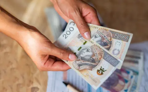 Dłonie trzymają banknoty 200 zł. Czy na lokatę można wpłacać pieniądze co miesiąc?