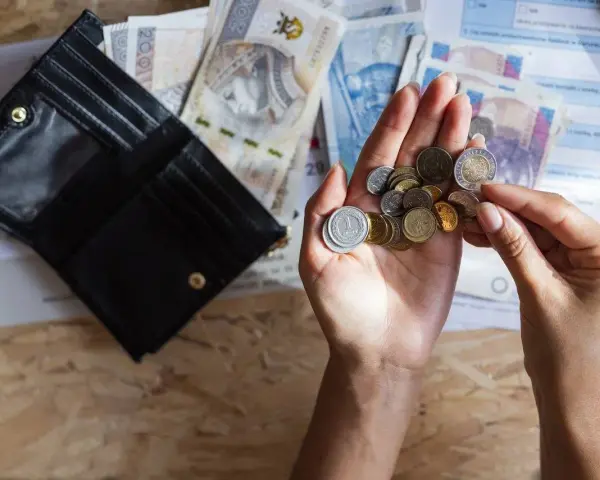 Dłonie liczą monety i banknoty obok otwartego portfela. Szybka, bezpieczna chwilówka to rozwiązanie, gdy brakuje gotówki.