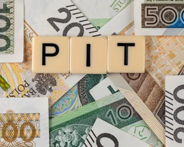 Litery "PIT" na tle polskich banknotów. Może oznaczać dużą niedopłatę podatku, która wymaga uzupełnienia.