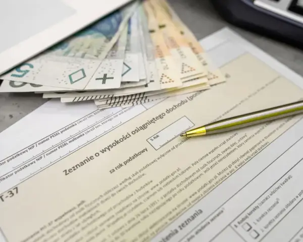 Pieniądze i długopis na formularzu PIT-37. Zbliża się termin rozliczenia, a kwota wolna od podatku ryczałt jest ważnym elementem zeznania.