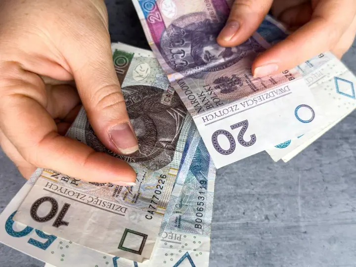 Ręce trzymają polskie banknoty 10, 20 i 50 zł. Czy w Vivus można przedłużyć pożyczkę?