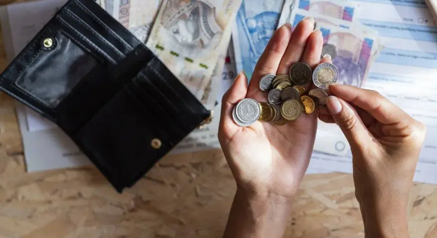Dłonie liczą monety i banknoty obok otwartego portfela. Szybka, bezpieczna chwilówka to rozwiązanie, gdy brakuje gotówki.