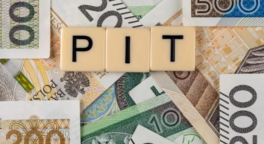 Litery "PIT" na tle polskich banknotów. Może oznaczać dużą niedopłatę podatku, która wymaga uzupełnienia.