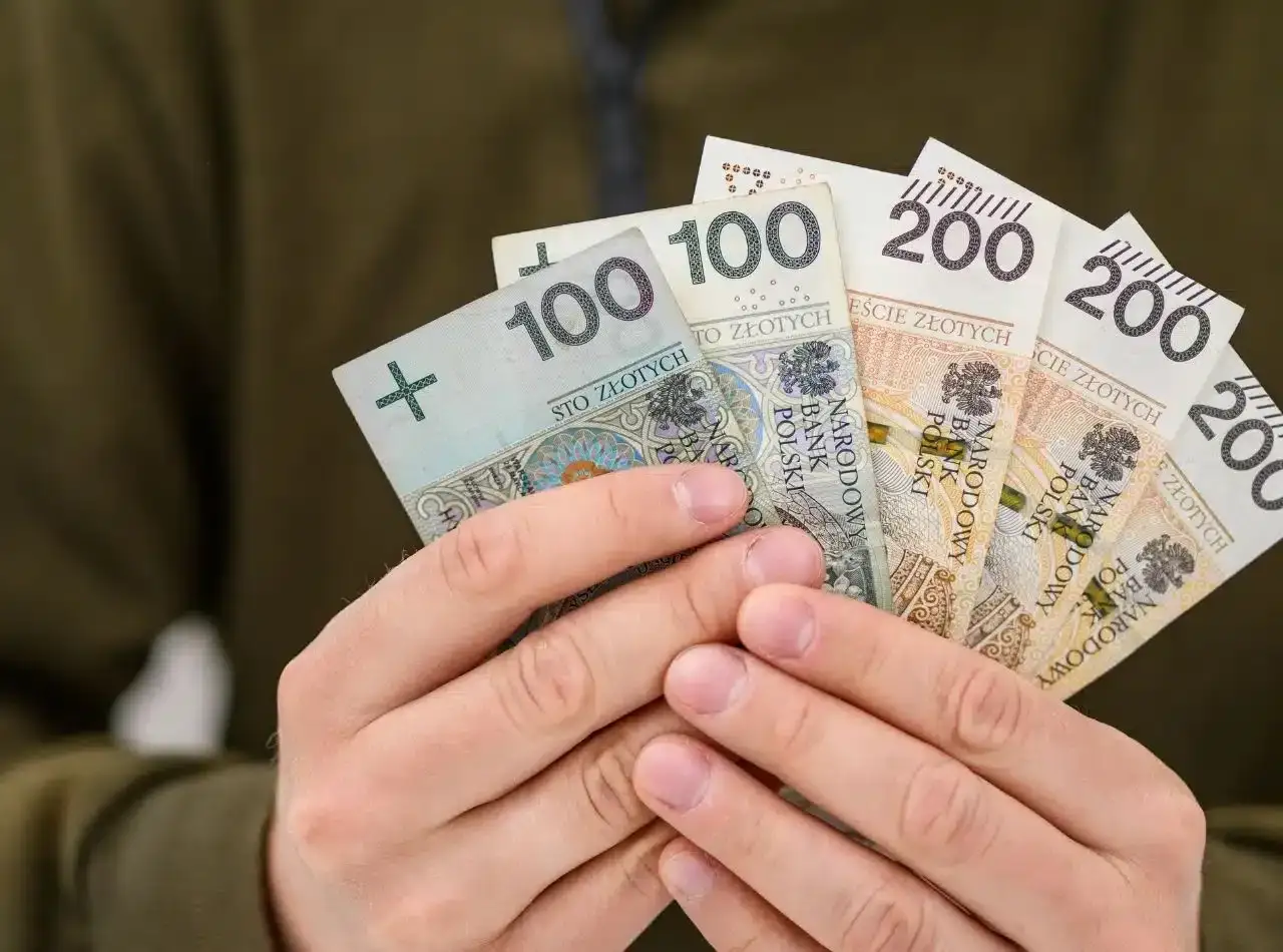 Dłonie trzymają polskie banknoty 100 i 200 zł. To może być kwota, która pokryje maksymalną prowizję za udzielenie pożyczki.