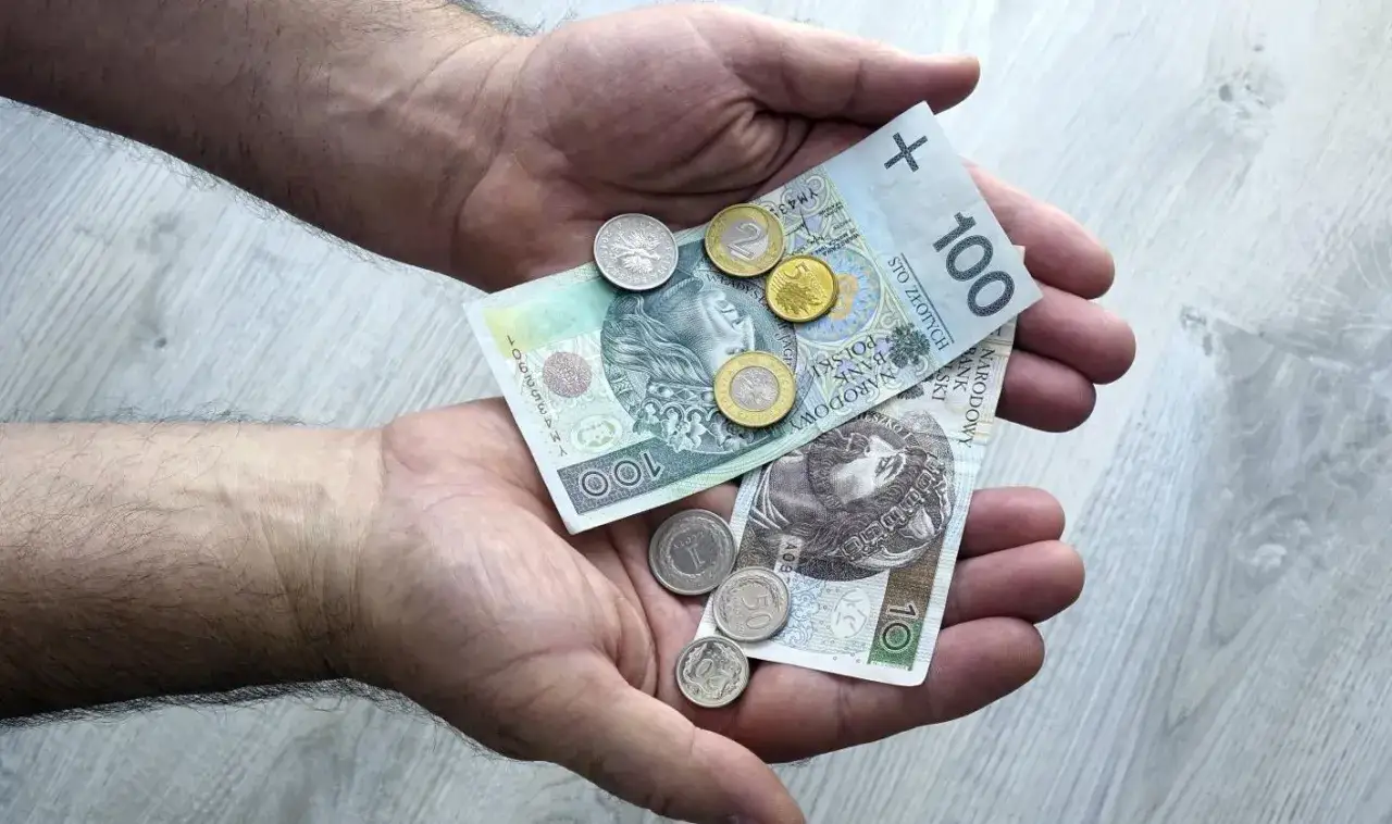 Dłonie trzymają polskie banknoty i monety. To pokazuje, co można sprzedać w lombardzie, gdy potrzebujesz szybkiej gotówki.